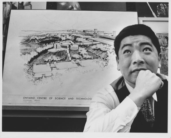 Raymond Moriyama with drawing of the Ontario Science Centre behind him, black and white