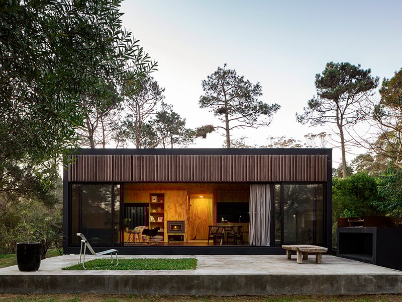 Exterior view of the cabin with the sliding glass doors open, showing the open concept living-dining area