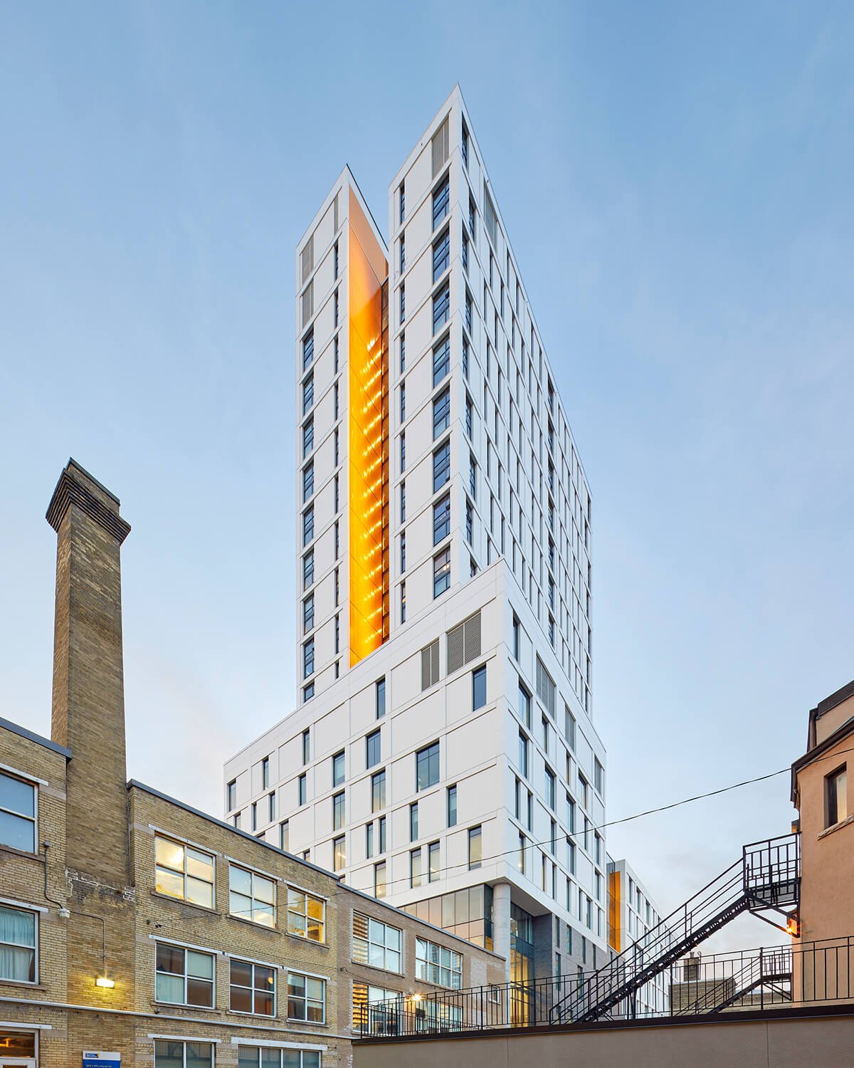 Exterior view of the building, showing its site context, split level podium, and residential tower.