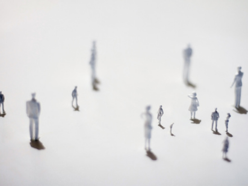 Miniature models of people scattered on white background