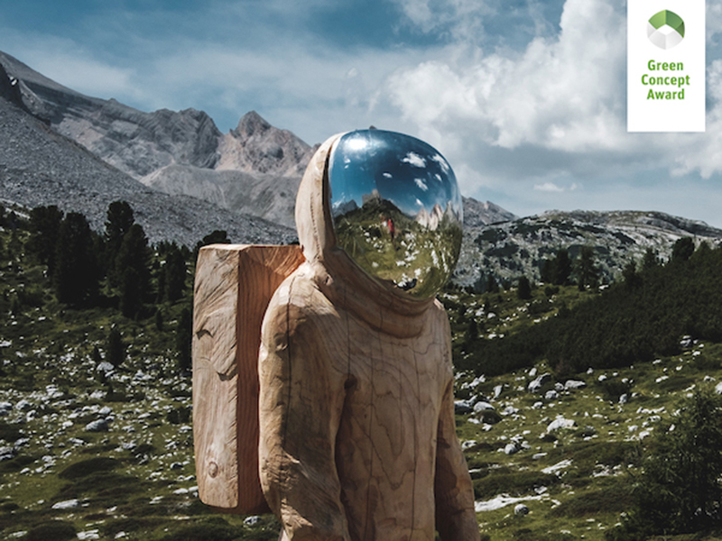 Person in wooden space suit standing in front of mountains