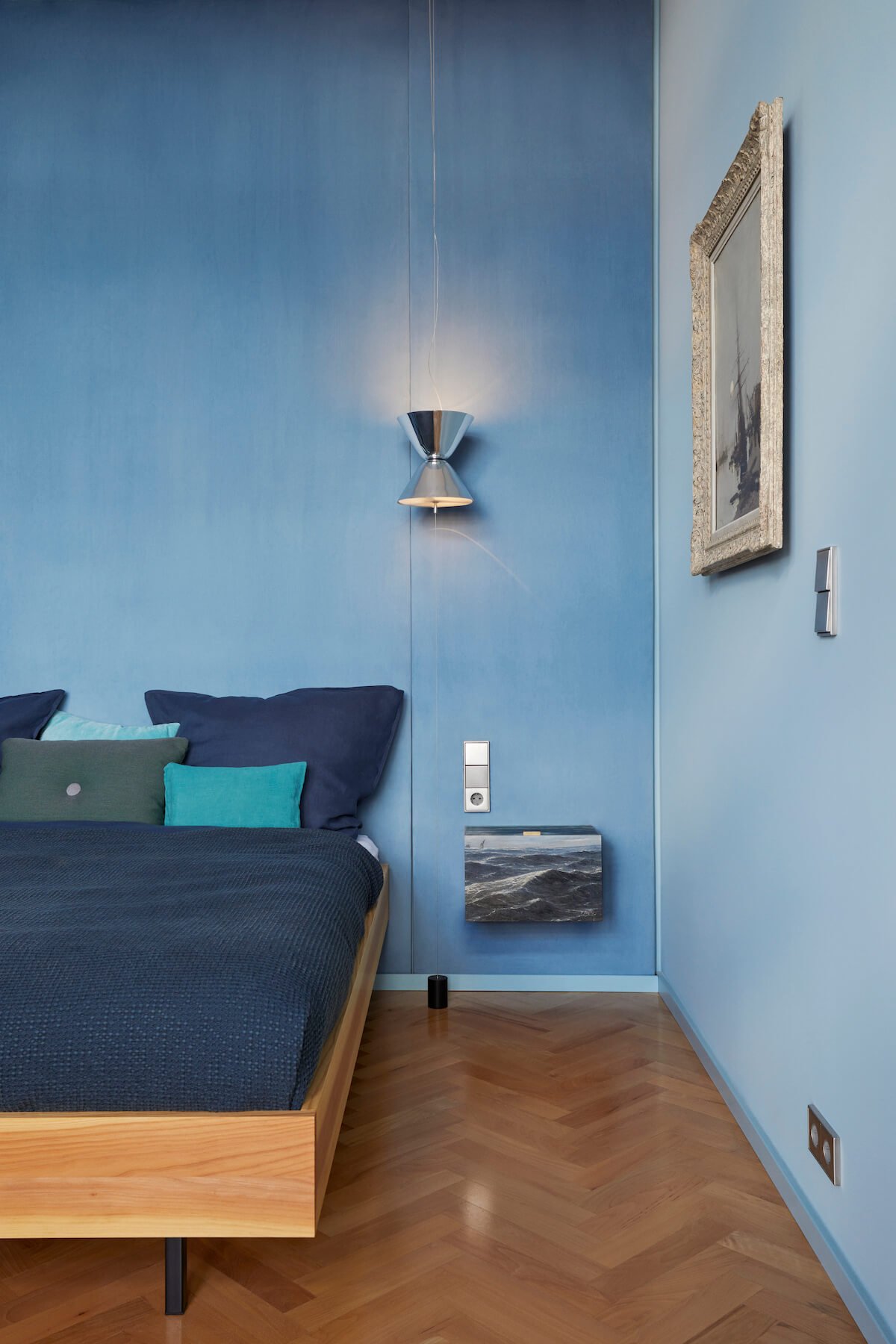 A close-up of the bedroom, where nautical paintings are set against blue walls.