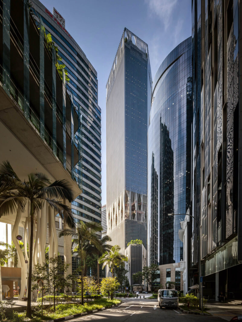 A distant, full-height view of the building, showing the green landscape at street level in the foreground
