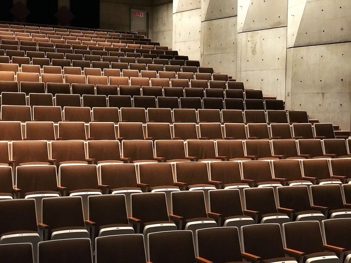 Rows of empty seats in a lecture hall with concrete wall in the background