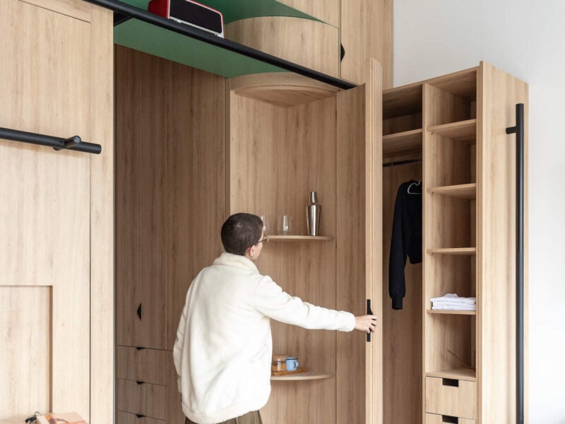 A woman opens a cabinet in the micro living concept Domestico