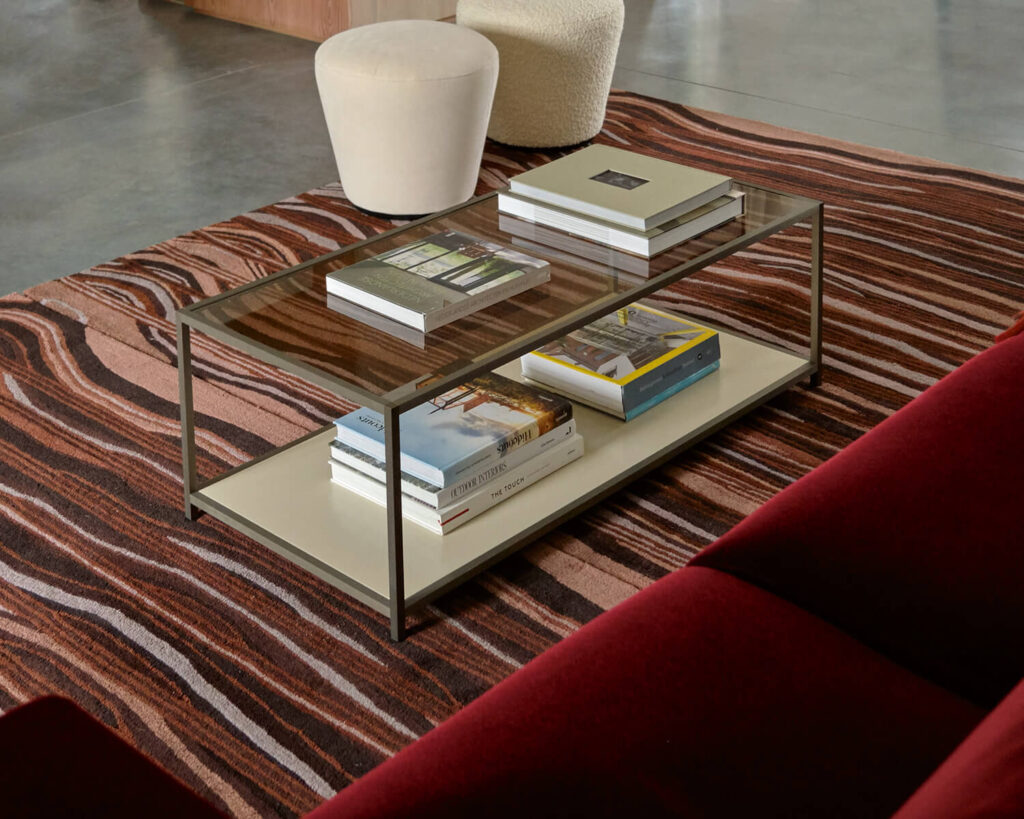 Rectangular coffee table with glass top and books stacked on top