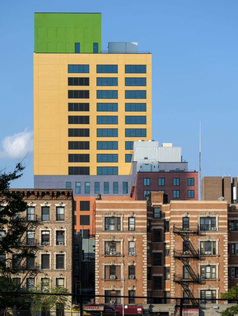 MVRDV's Radio Hotel and Tower, a stack of multicoloured boxes, is shown rising above Washington Heights apartment buildings.