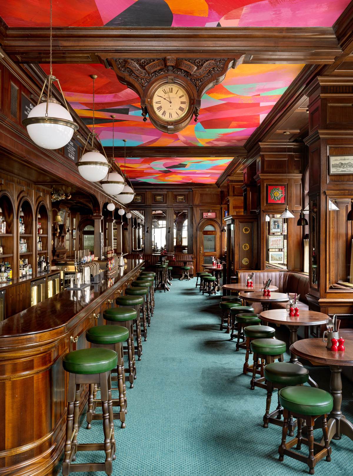 The ground floor pub in The Audley London, featuring dark wood and a bright ceiling mural.