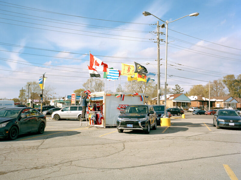 A vendor sells colourful flags in a strip mall parking lot during World Cup 2022.
