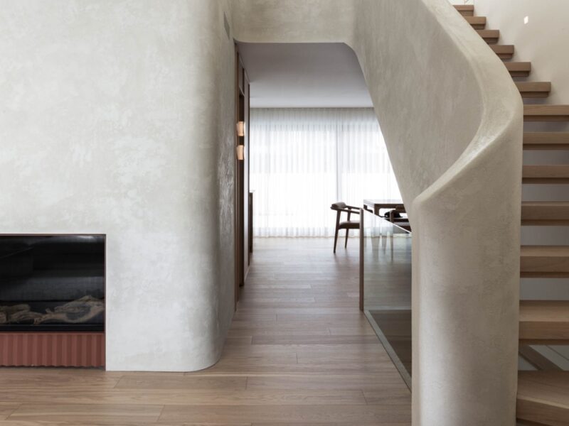 A lime plaster staircase curls into a large volume that contains a fireplace in the living room of a Montreal home renovation by Ménard Dworkind.