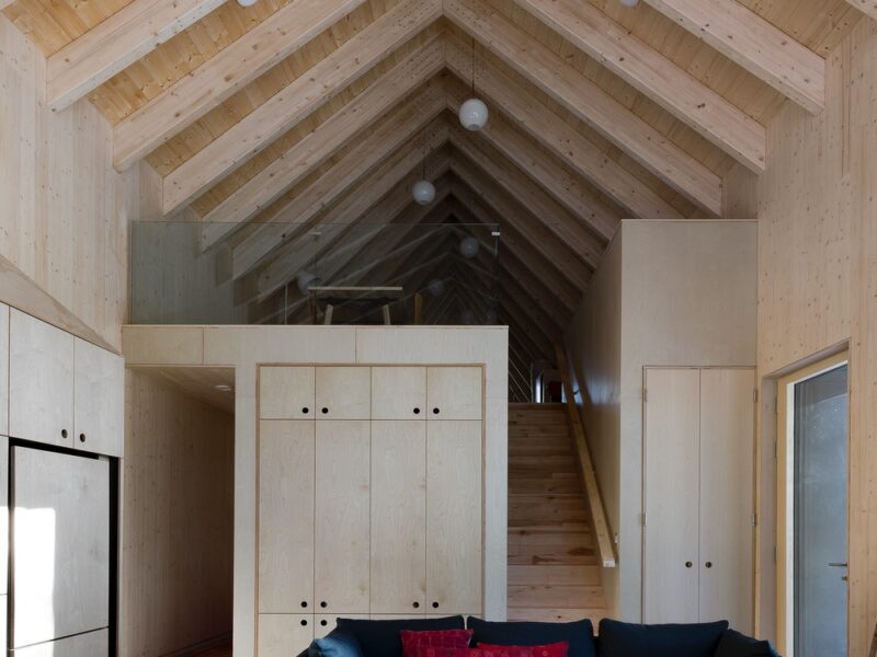 A view towards the stairs and upstairs loft in a pending Passive House in Ontario that features glulam rafters that grow gradually steeper.
