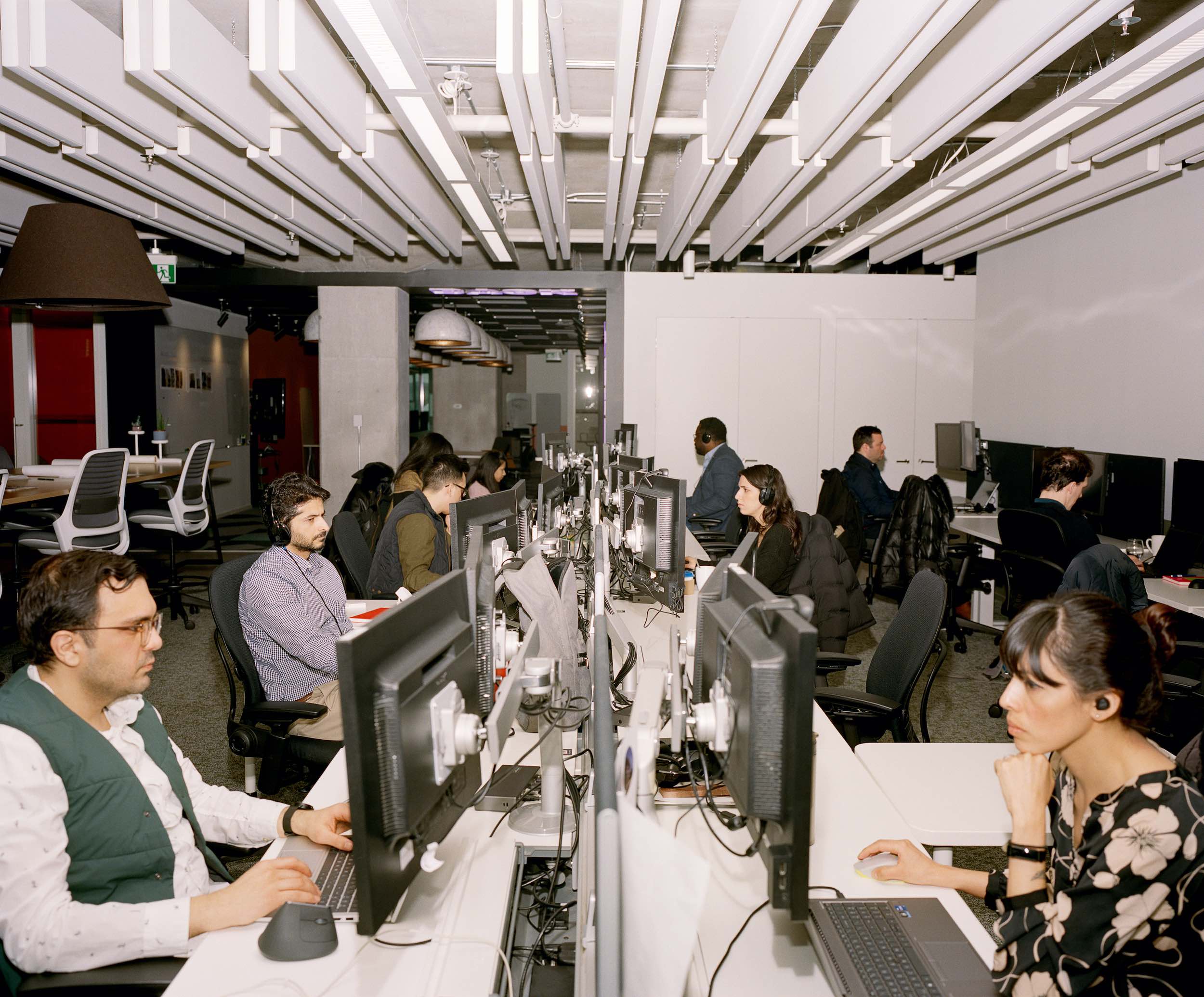A group of office workers sit in a row at their computer terminals. Part of a return to office photo series shot in Toronto.