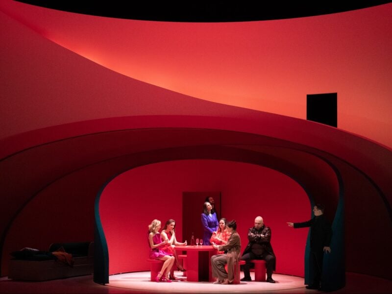 A series of curved stage partitions designed by Pierre Yovanovitch encircle a group of actors performing Rigoletto.