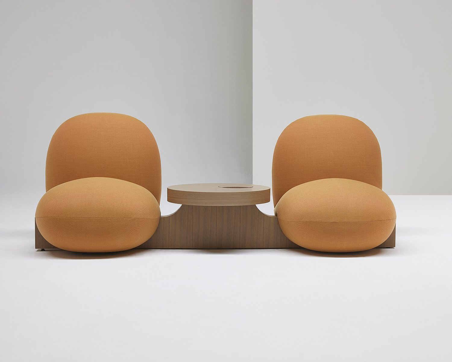 Two orange seats with a round wooden table in between
