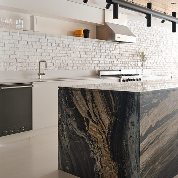Montreal studio La Firme appointed the new kitchen with an island made from four slabs of Dedalus marble, whose dramatic streaks of black, beige, grey and green tie the room together.