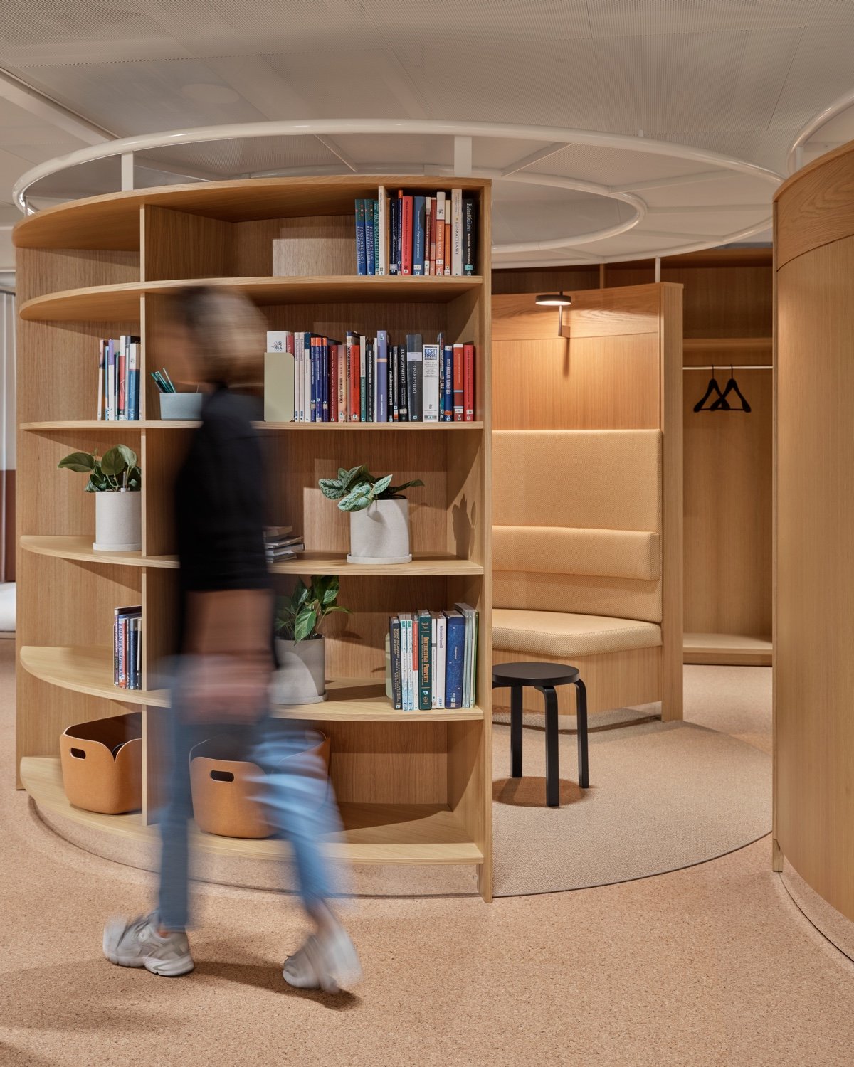 Curved wooden bookshelf with seating behind