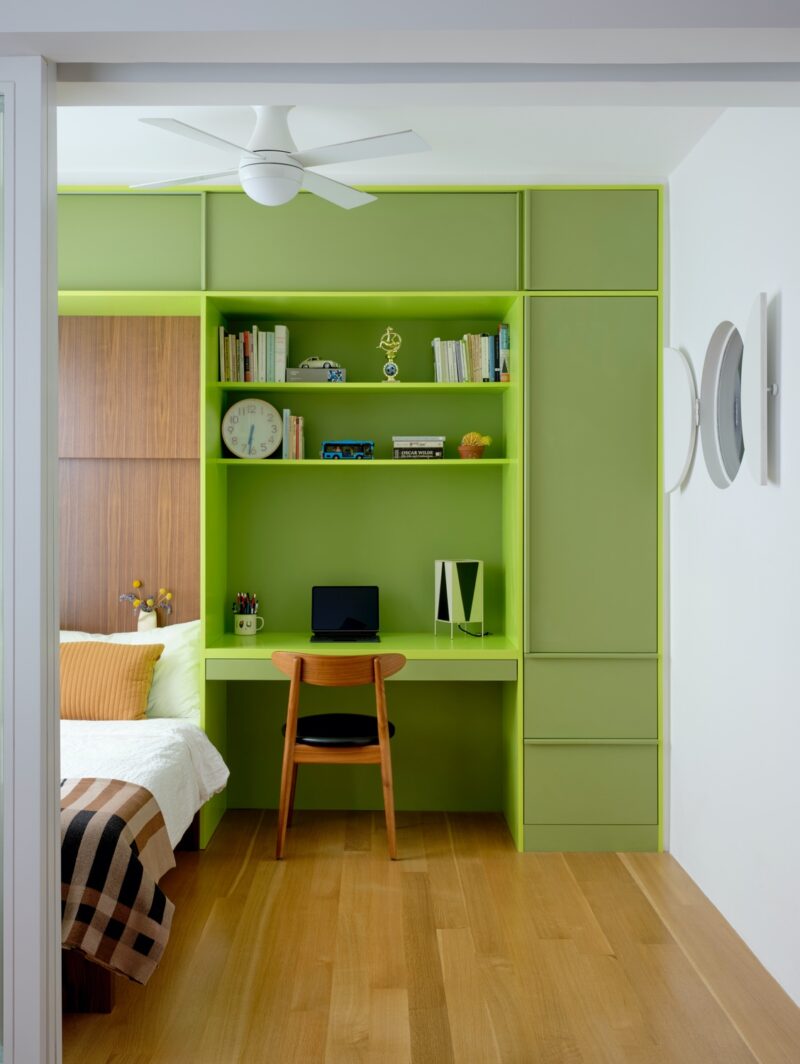 Lime green millwork creates shelving, a desk and a bed against the back wall of an NYC apartment reno by Ideas of Order Studio.