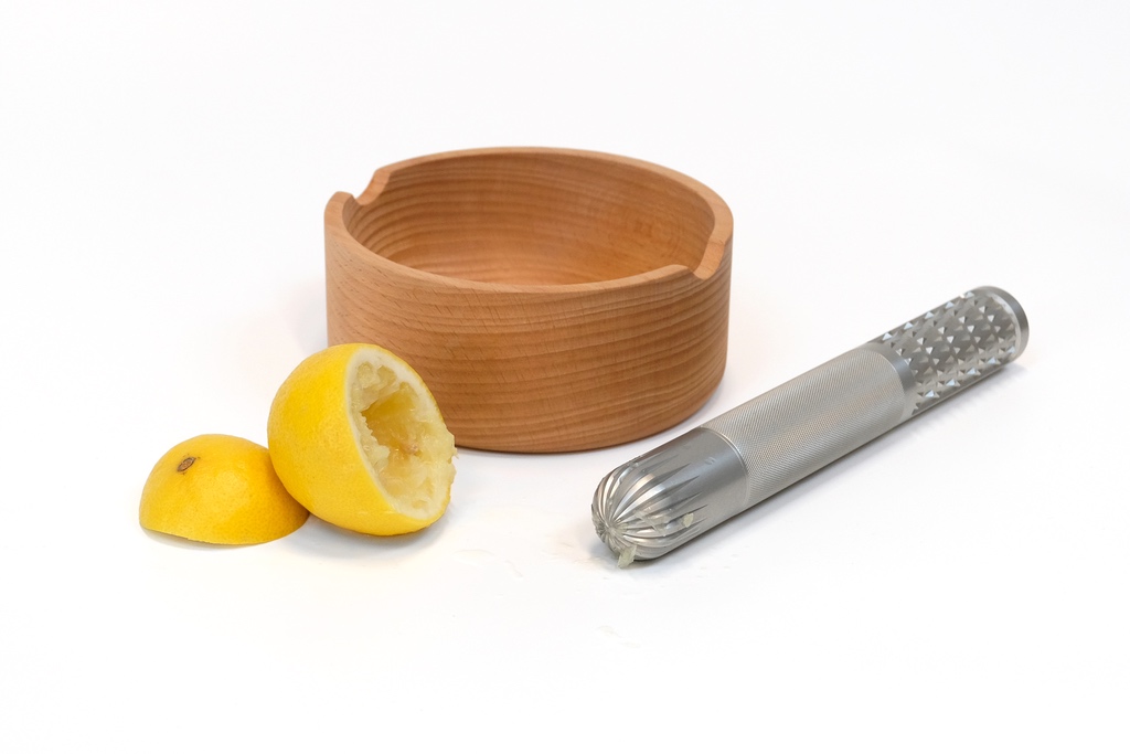 A wooden bowl and an aluminum cylinder with a variety of patterns designed for zesting and squeezing citrus. The product is made by Matheson, a homeware brand led by Matty Matheson, and the designer is Toronto studio Castor.