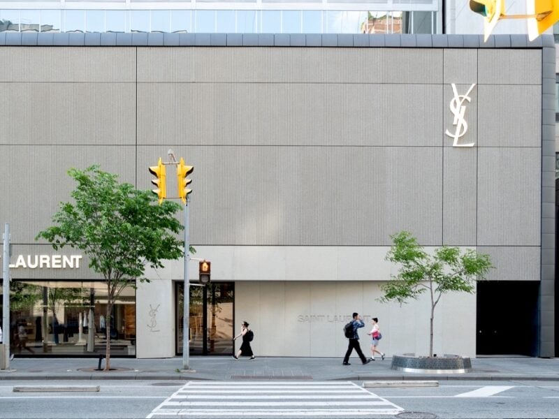 A view of the YSL Saint Laurent store on Bloor Street in Toronto from across the street. The store is covered in concrete panels in the style of brutalist architecture, with the top half featuring a striated texture and the bottom a smoother finish.