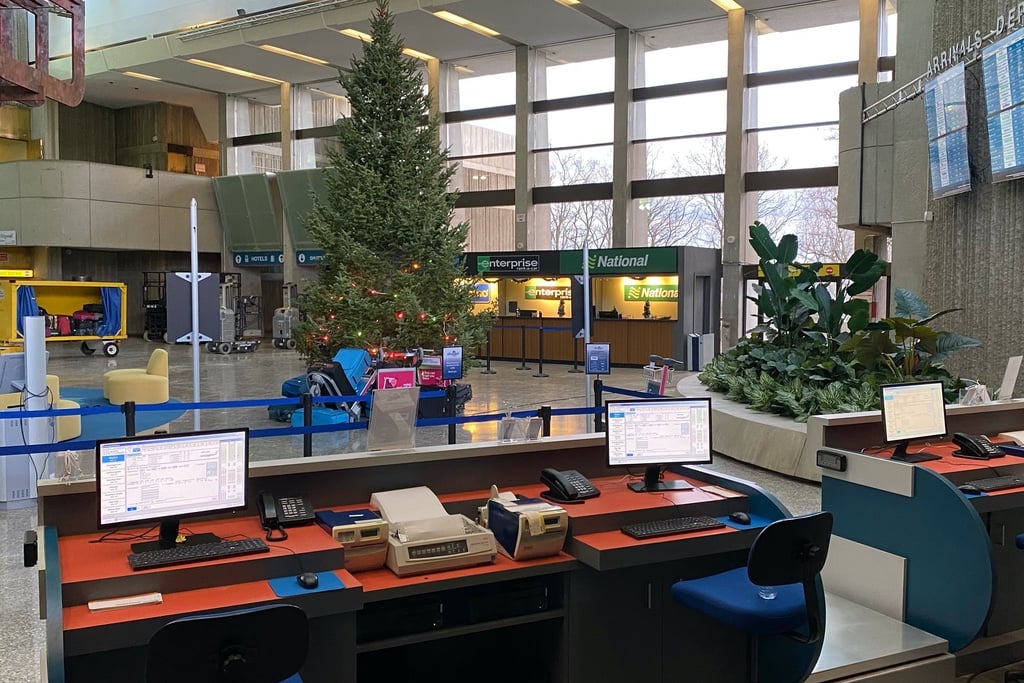 A photo of the Severn City Airport set from Station Eleven showing airline check-in desks, car rental kiosks and a large Christmas tree stationed inside of the brutalist Ontario Science Centre.