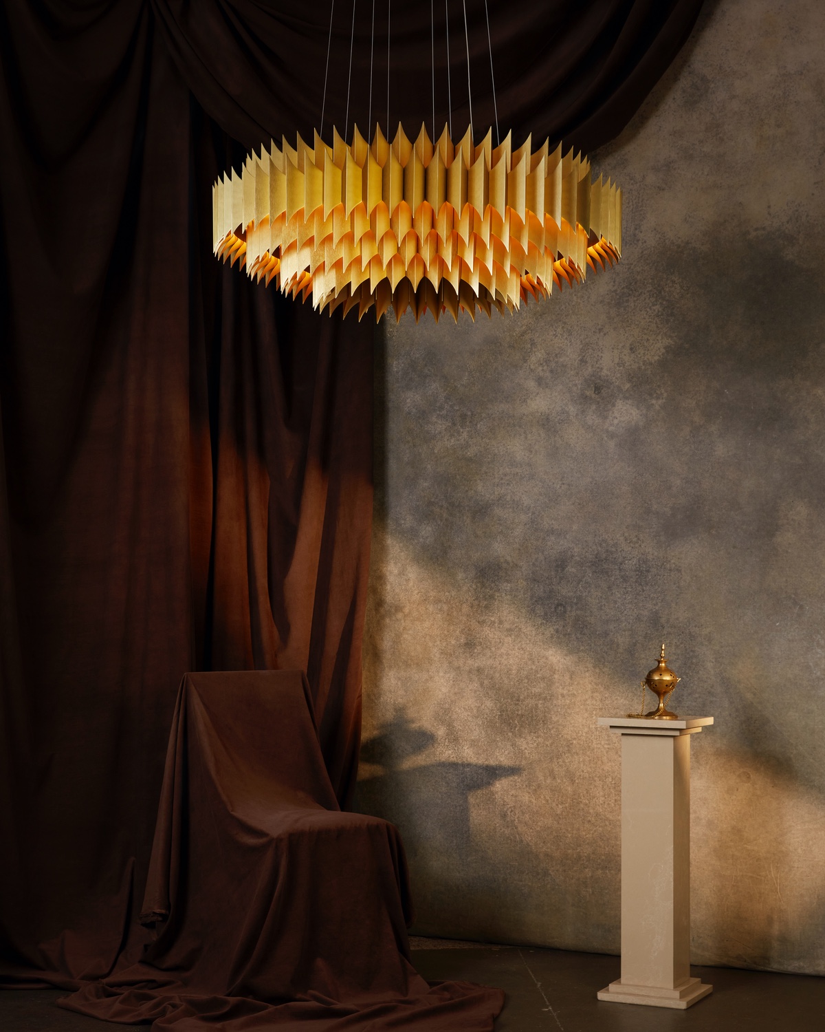The King chandelier from the Alchemist collection by Lee Broom features several rings of small aluminum leaves that have been joined together. It glows from within.