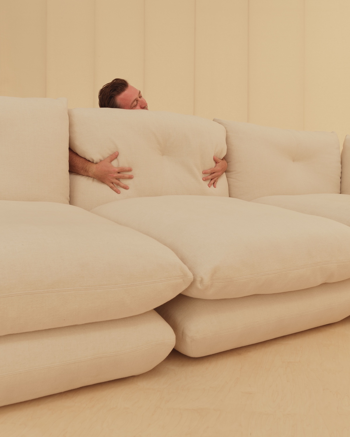Designer Willo Perron hugs one of the cream-coloured pillow-like cushions that form the Pillo sofa by Knoll.