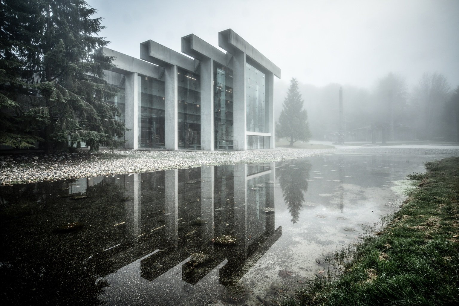 An exterior view of the Museum of Anthropology designed by Canadian architect Arthur Erickson. The building features four concrete gates with glass between them. It's shown on a misty grey morning.