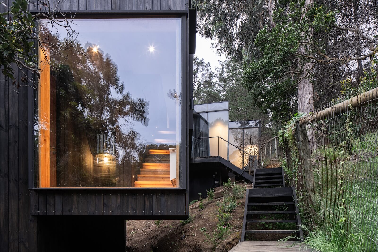 At the end of the bridge, a floor-to-ceiling window provides a view of the bay. Inside, the staircase connects to the primary bedroom.