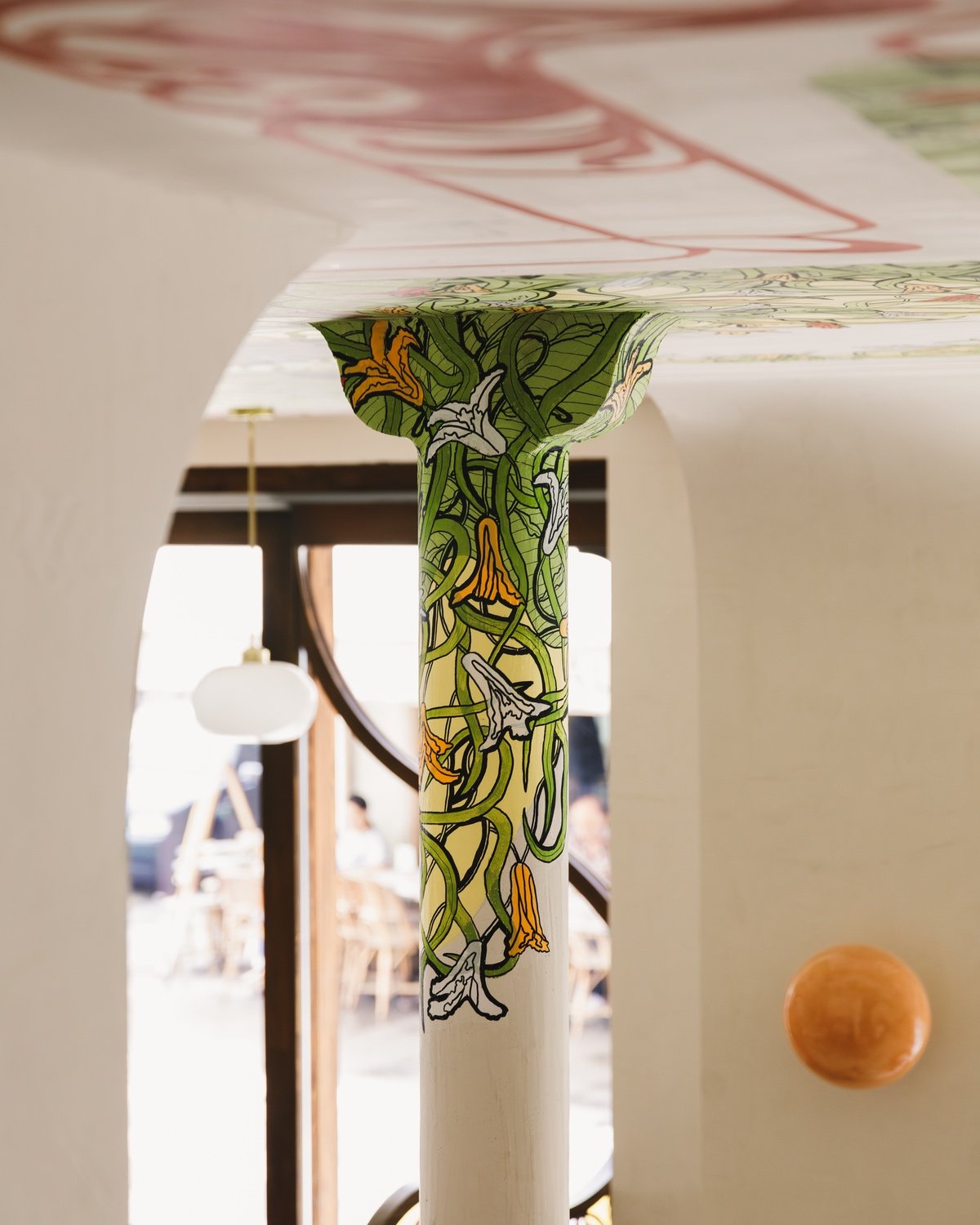 A floral mural runs along a column at Adela pasta restaurant in Paris.