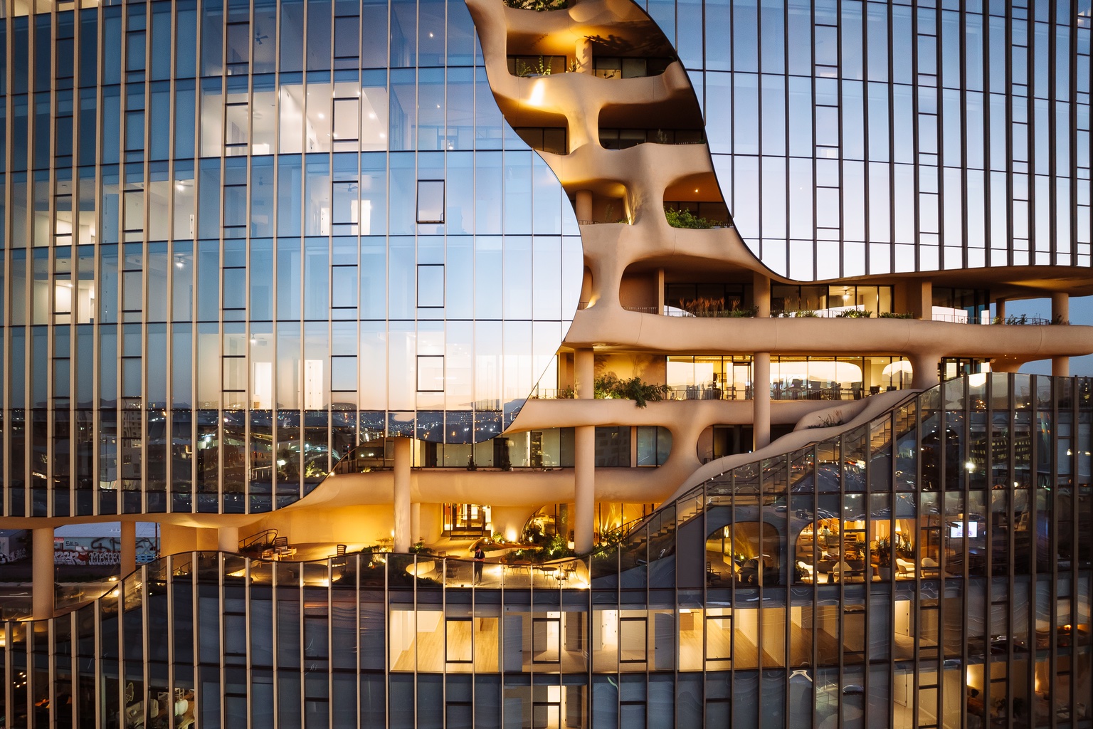 The glass facade of One River North in Denver, with the facade dipping back at certain points to form an exterior hiking trail.