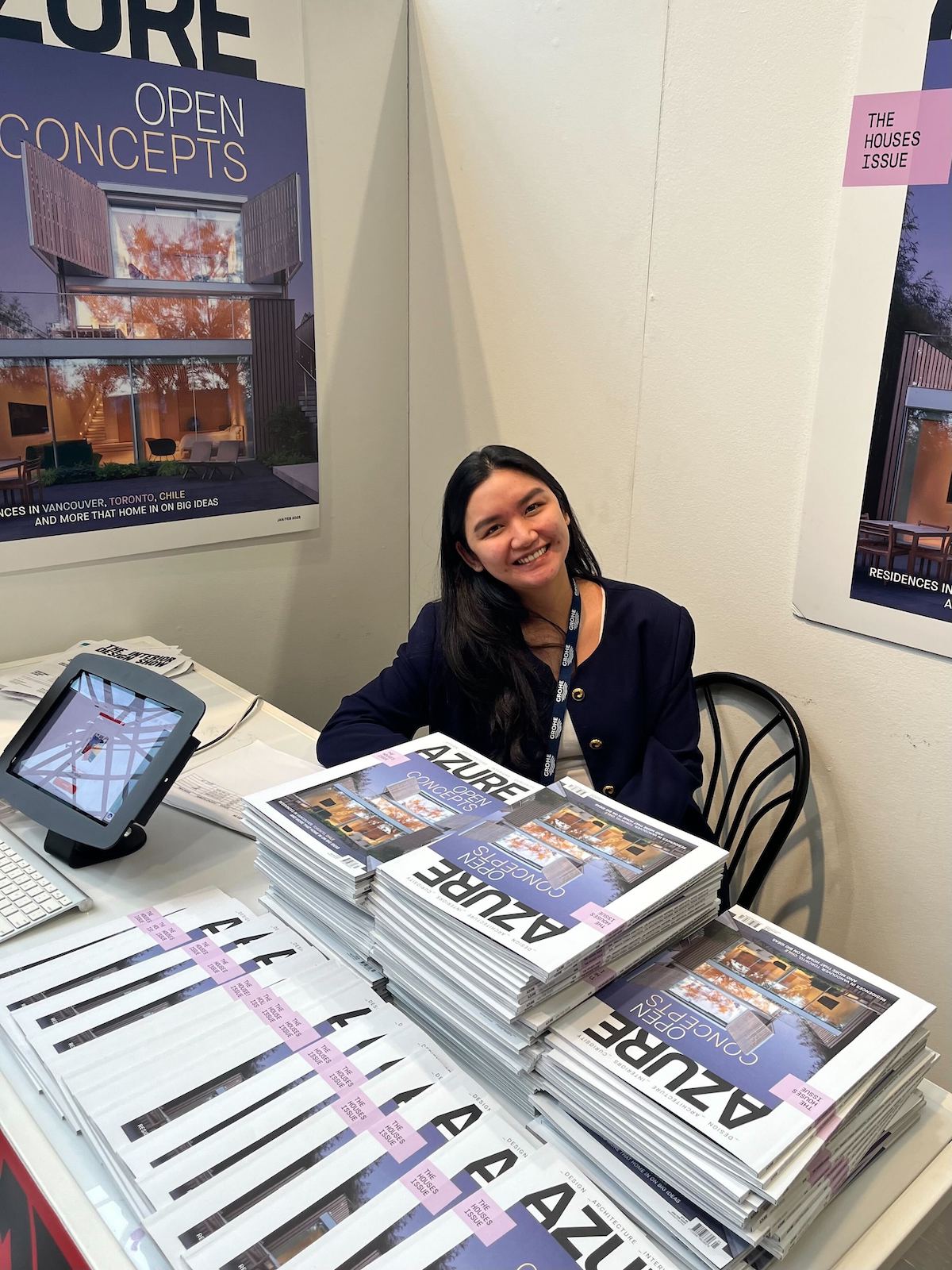 Inie Borlaza of Azure smiling while sitting behind stacks of Azure in the magazine's IDS 2025 booth.