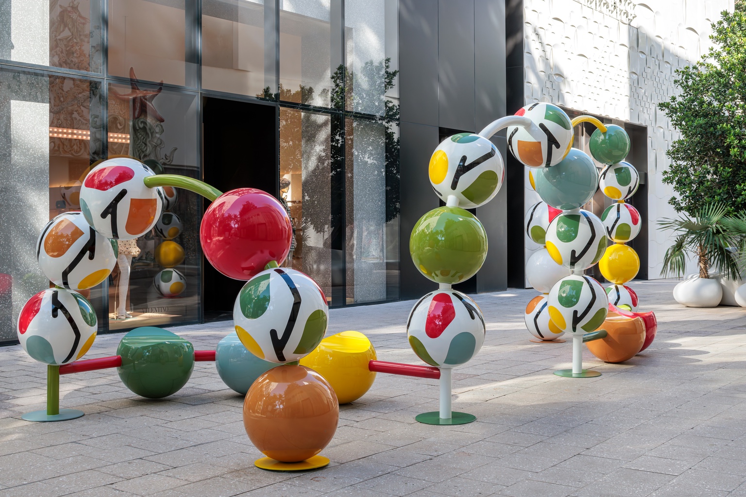 An arched outdoor sculpture featuring giant patterned beads running along a metal track — one of the best designs of Design Miami and Alcova Miami 2024.