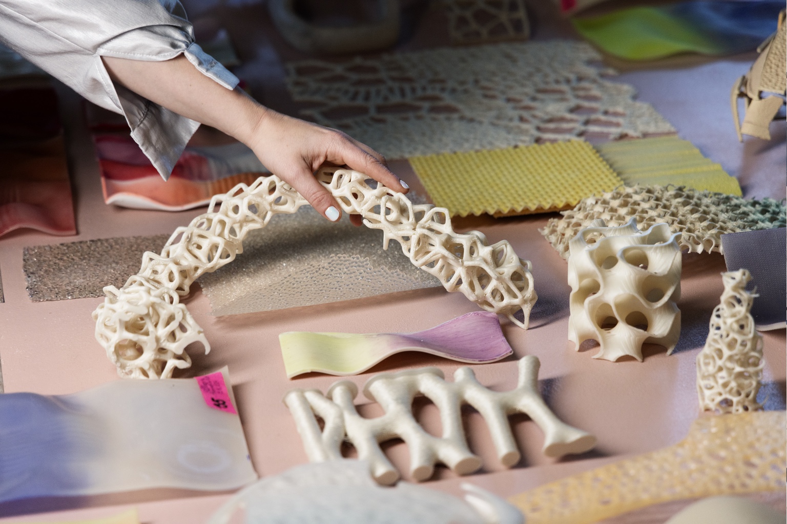 A hand grips a skeleton-like sculpture made from biomaterials.