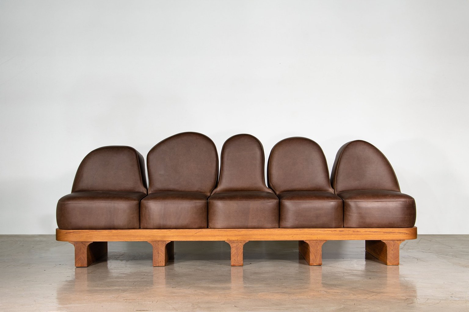 A piece of furniture designed by Michael Bennett, a sofa featuring leather backrests shaped to resemble people seated in a church pew.