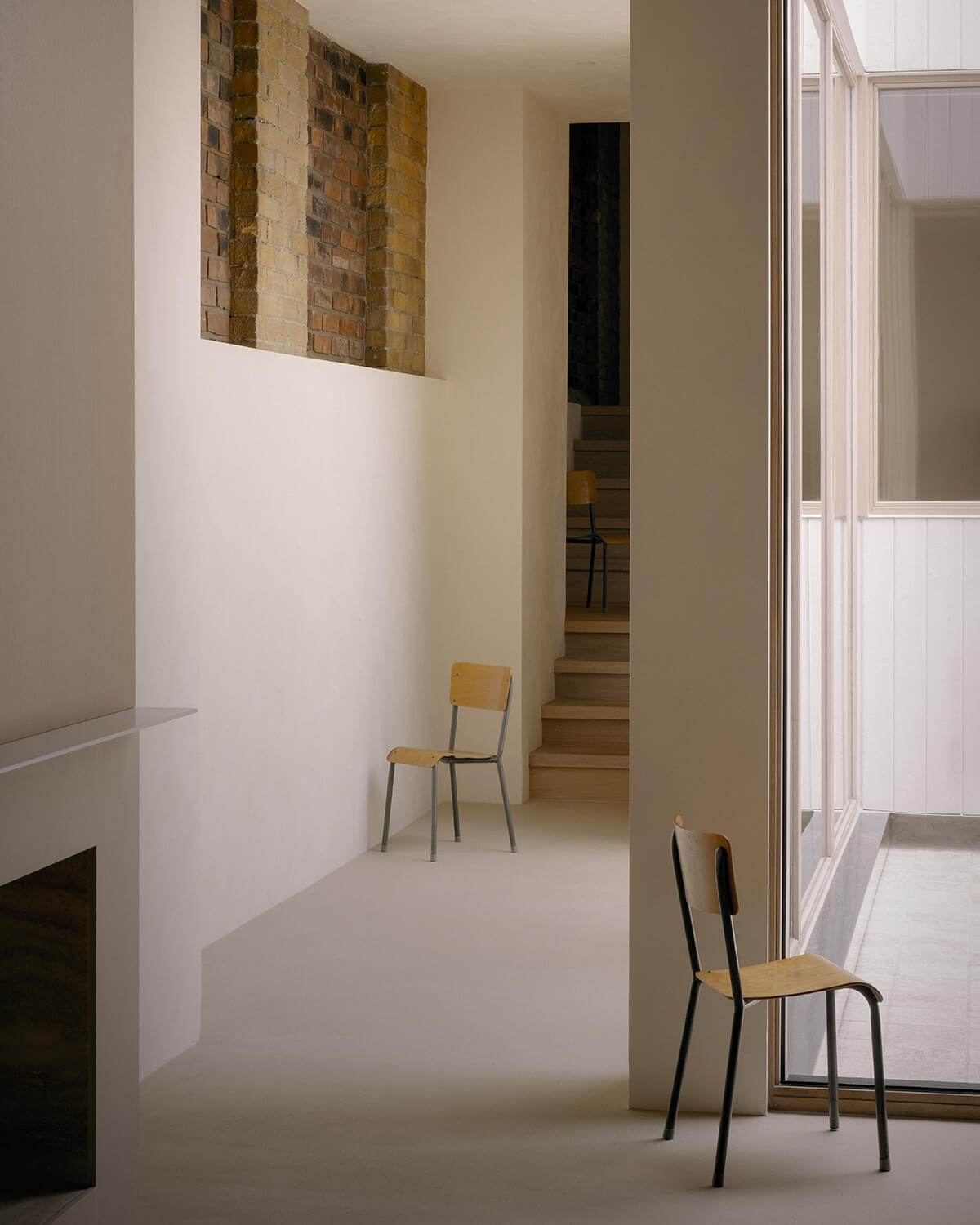 The brick walls of the original foundations peek through as a datum line in the hallway of StudioAC's Junction Semi project