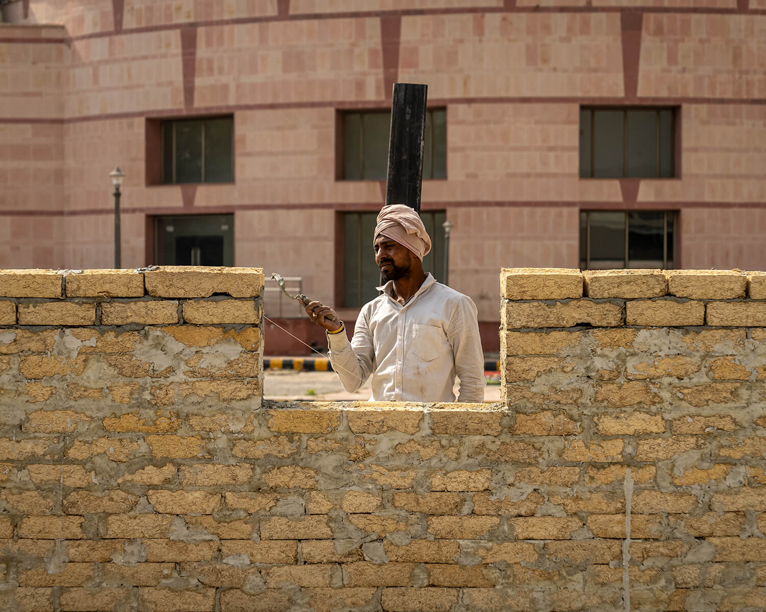 A worker builds a wall using Sugarcrete blocks (samples of which are shown at right) at a school in India, the first prototype building to use the material.