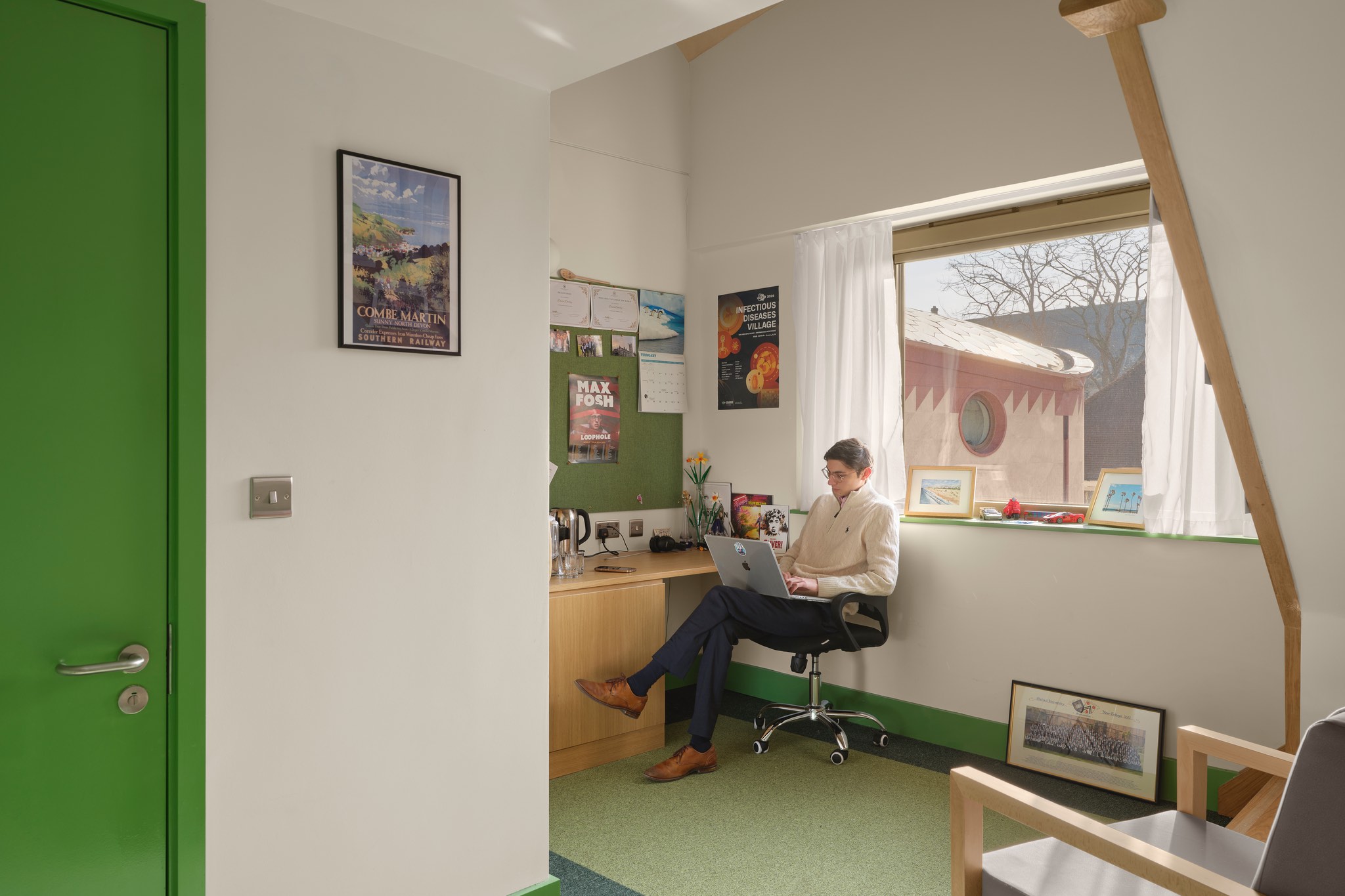 A student sits on a chair in his dormitory room at Gradel Quadrangles.
