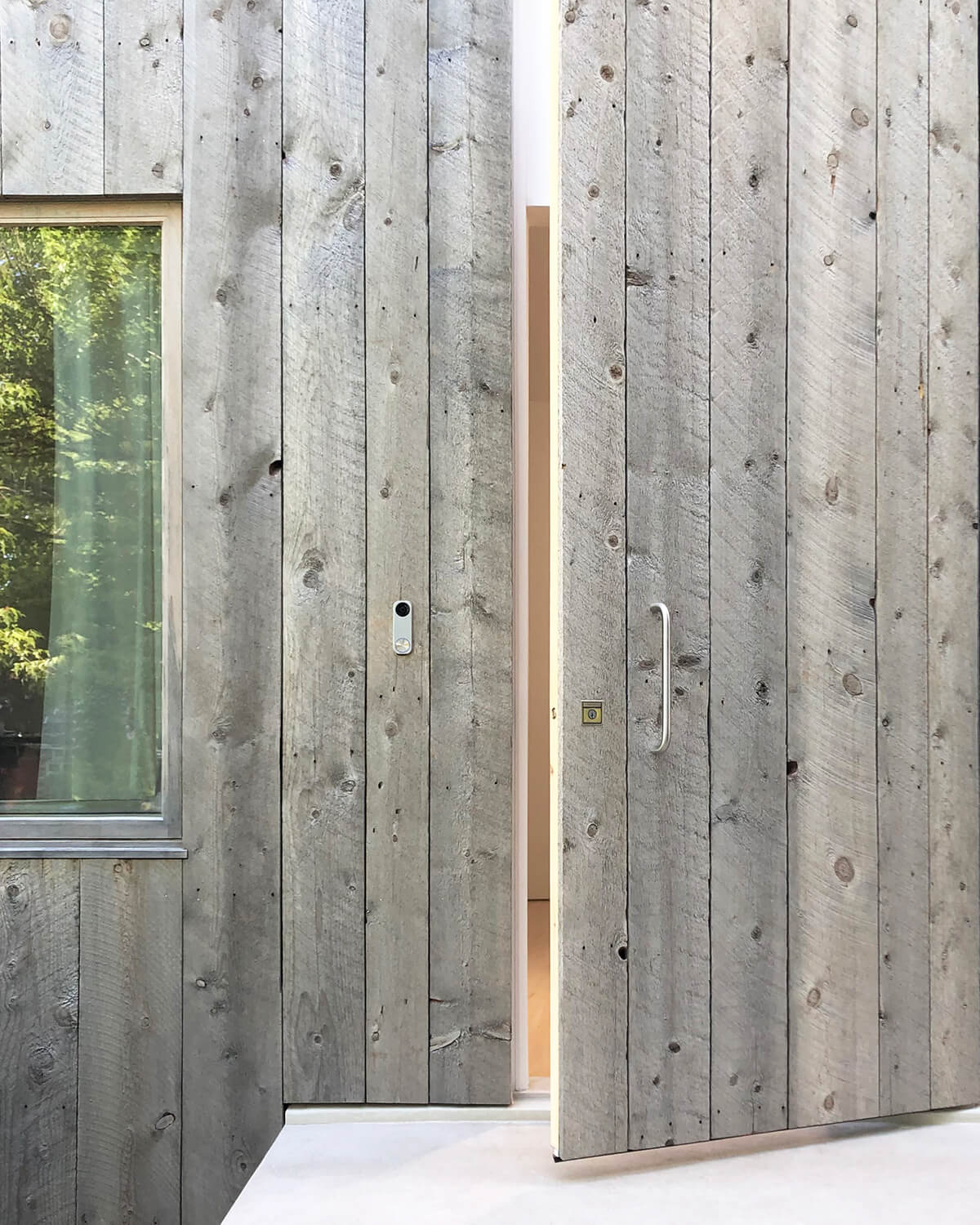 The front entrance is almost concealed by the silvery planks that blend in with the facade.