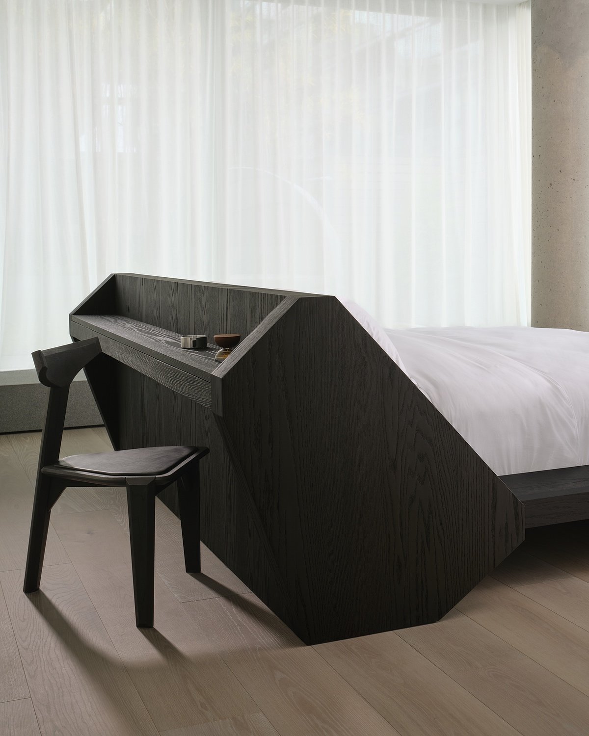 An desk integrated into the end of a bed frame with a wooden chair seated in front of it inside the King West Toronto condo owned by record producer and OVO Sound co-founder Noah "40" Shebib designed by Reflect Architecture.