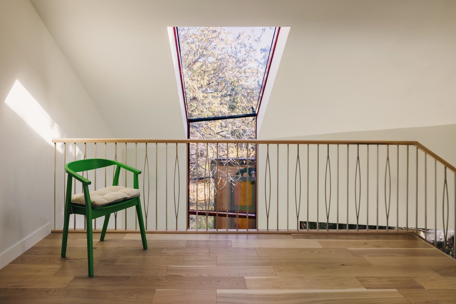 A balustrade with decorative spindles. Behind it is an angular window that runs from the roof down the wall.