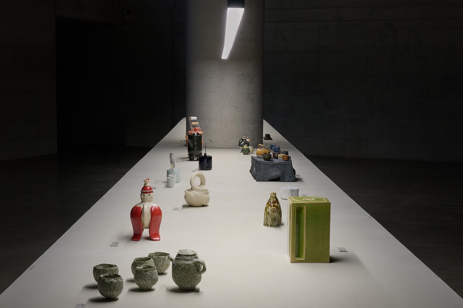 A lineup of various teapots on a white table as part of a Milan 2025 exhibition by Loewe.