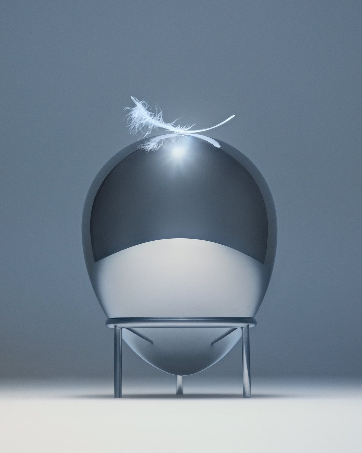 A metallic egg topped by a feather.