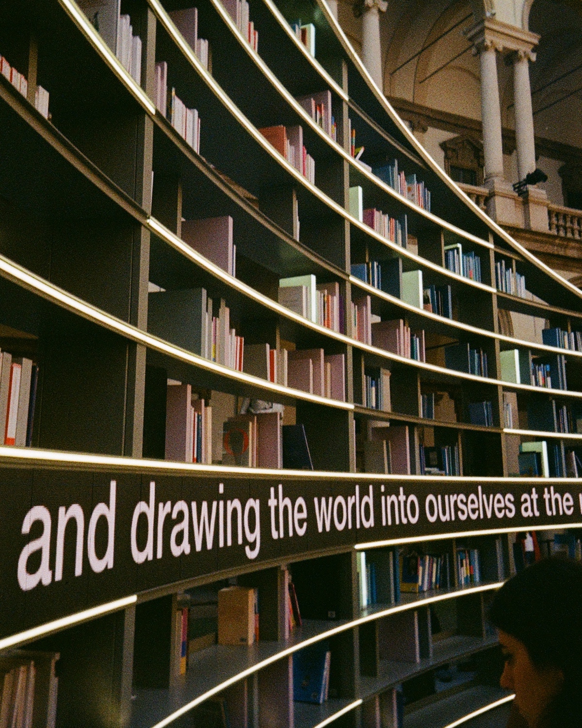 The Library of Light installation by Es Devlin during Milan Design Week 2025 featuring a rotating bookshelf with a screen displaying excerpts from the books shown.