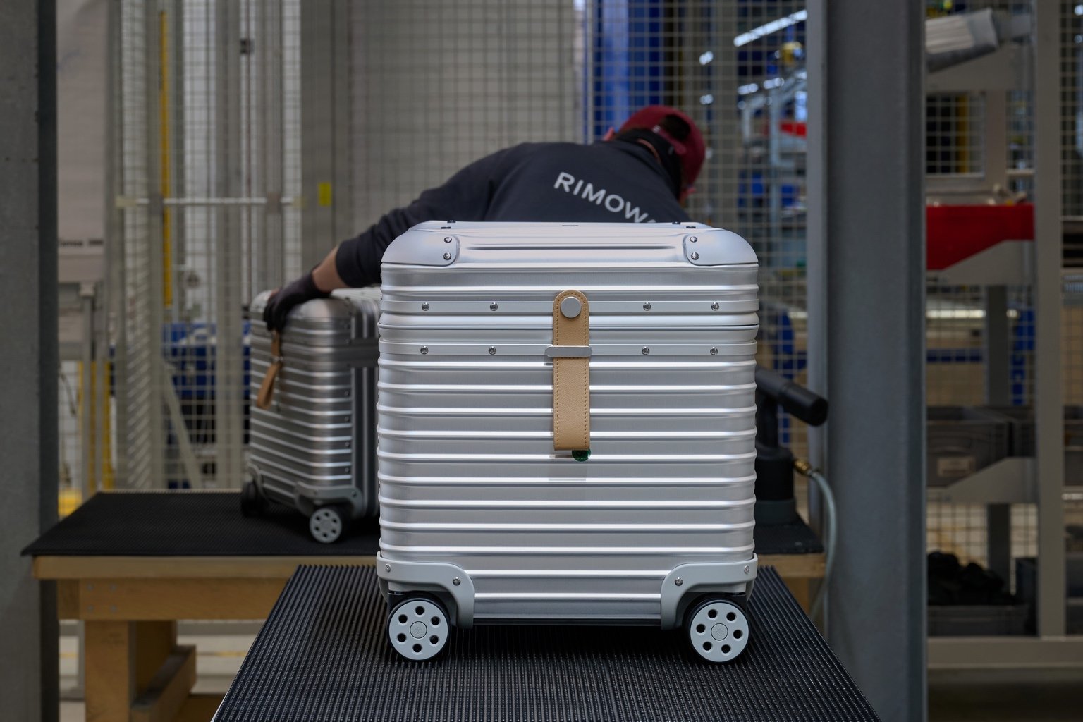 A Vitra Rimowa Aluminum stool modelled after grooved aluminum Rimowa luggage, with wheels on the bottom and a leather handle.