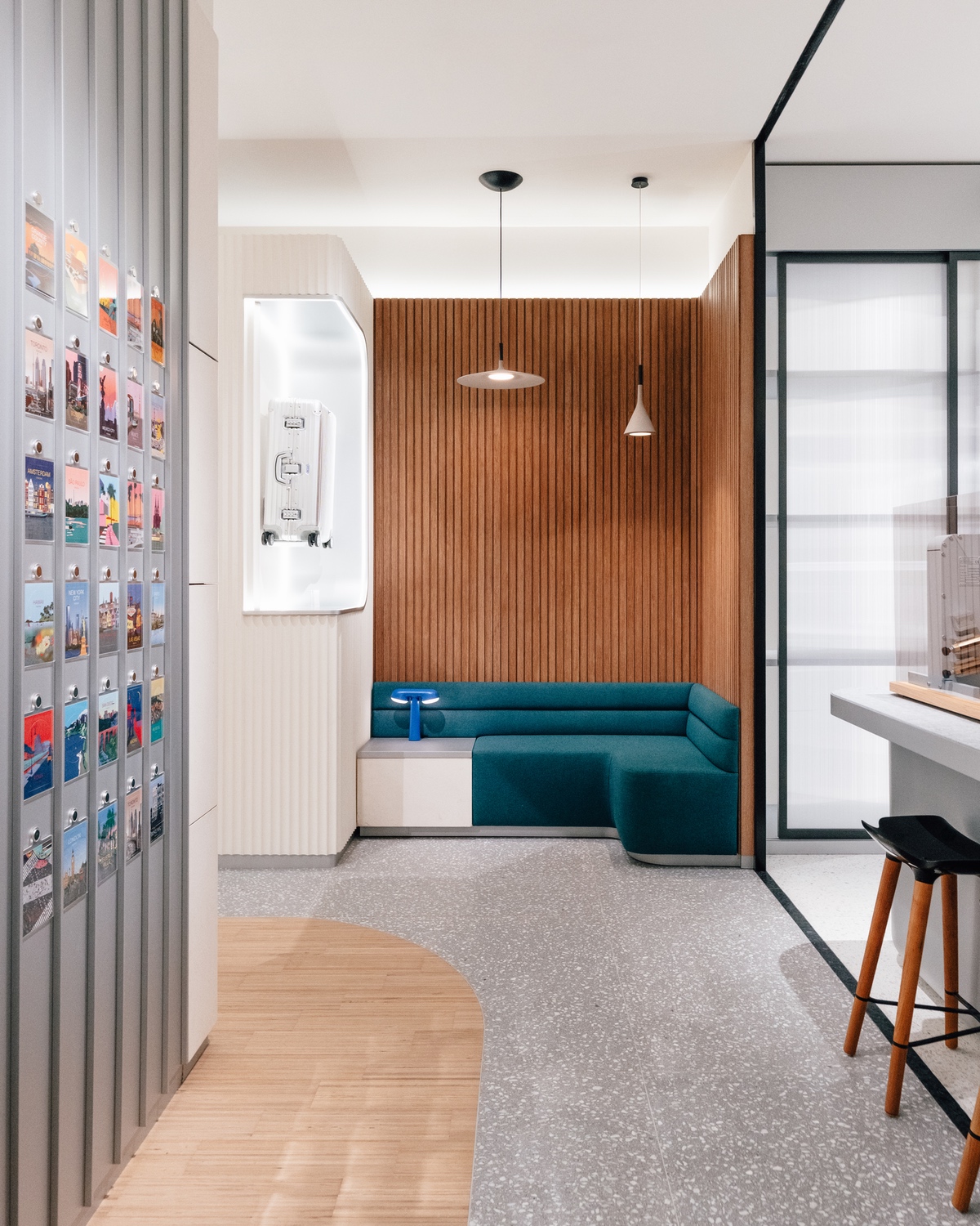 The interior of Rimowa's new store at Yorkdale mall in Toronto, showing a grooved wooden wall with a green sofa below it. To the left is a grooved aluminum wall covered in stickers.