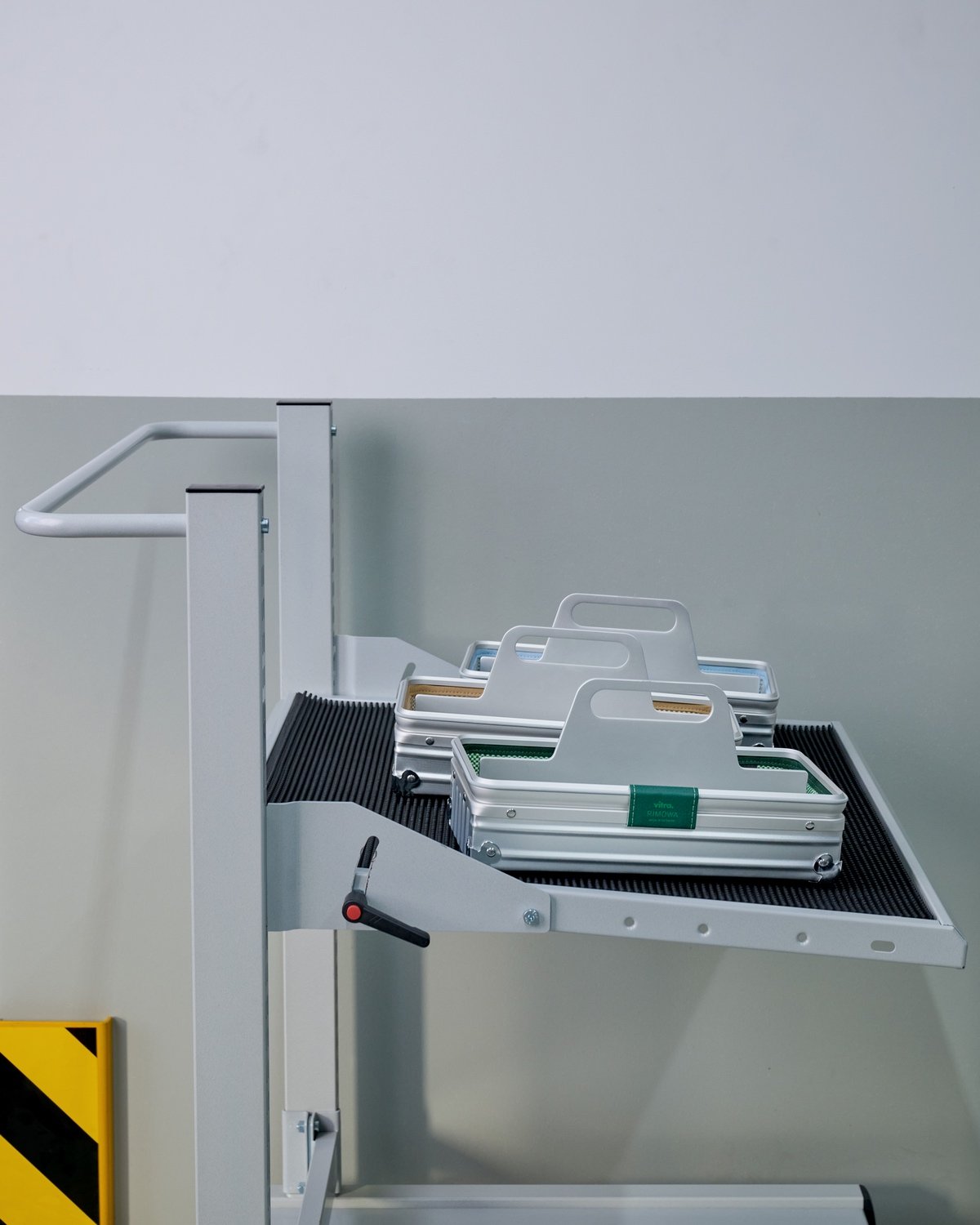 A trio of grooved aluminum Rimowa Vitra toolboxes sit on an aluminum cart in a factory.