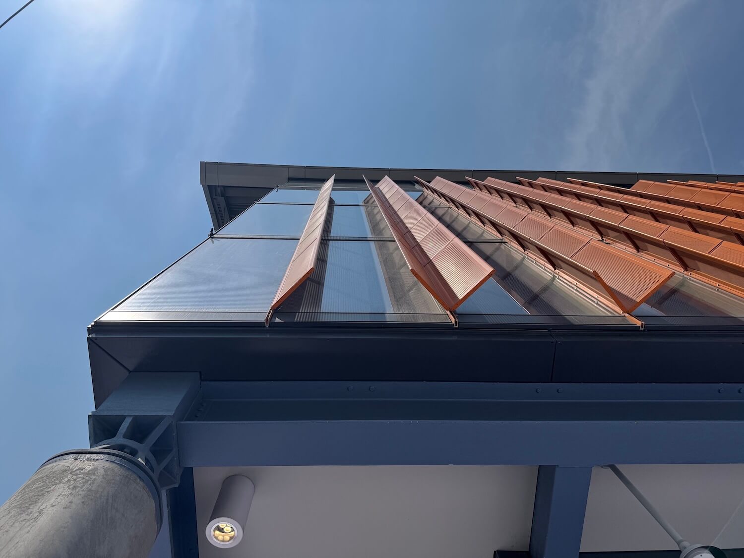 The angled orange fins — which risk feeling tacked on at the hands of lesser designers — mitigate solar heat gain. Worm's eye view of the east facade.