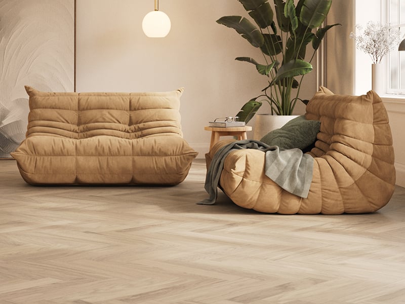 Woodura Herringbone 2.0 by Bjelin under two brown couches and a large plant behind them