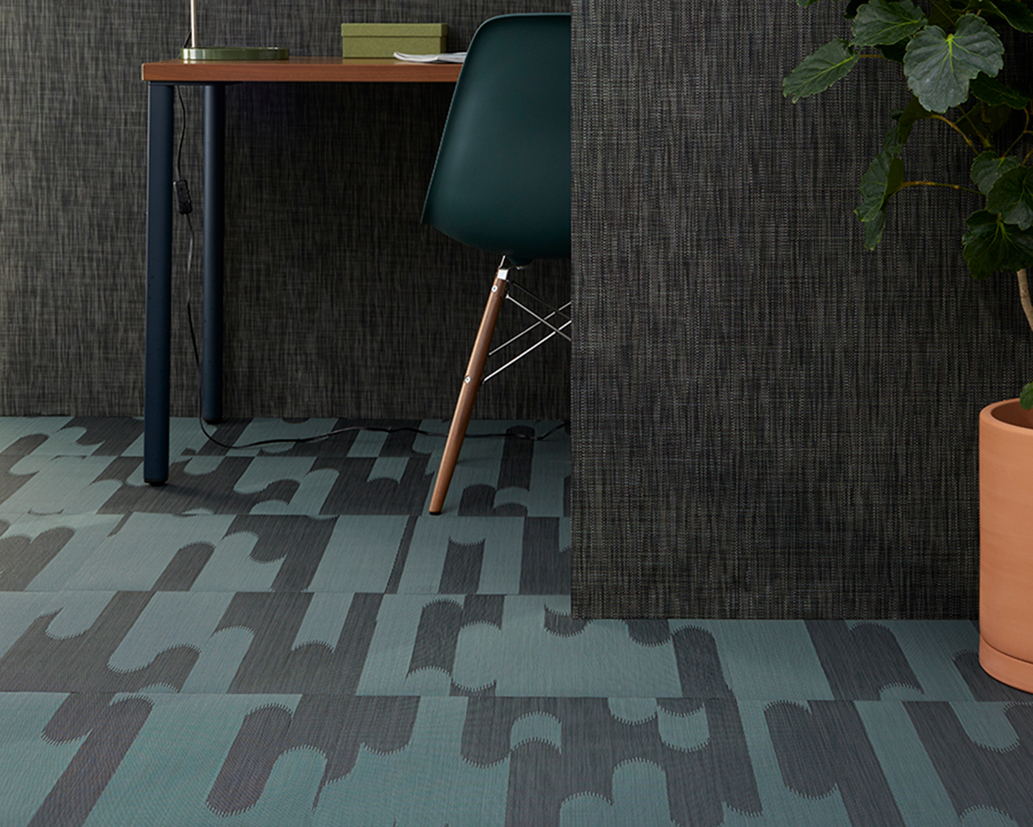 Green and black Shuttle carpeting by Chilewich with a potted plant and desk