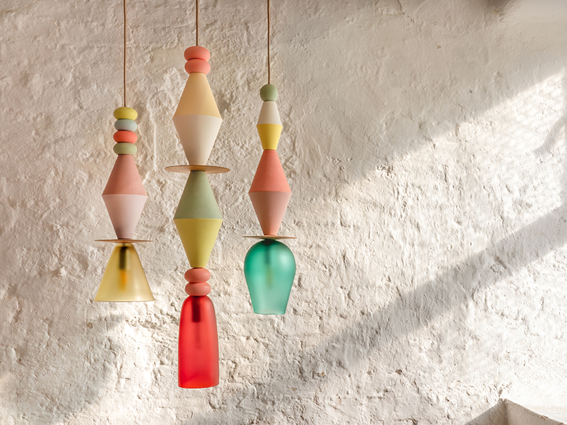 White wall with a window shining light on three colourful lamps